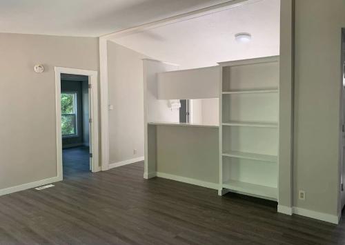 An empty room with hardwood floors and a bookcase.