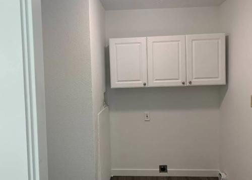 An empty room with white cabinets and hardwood floors.