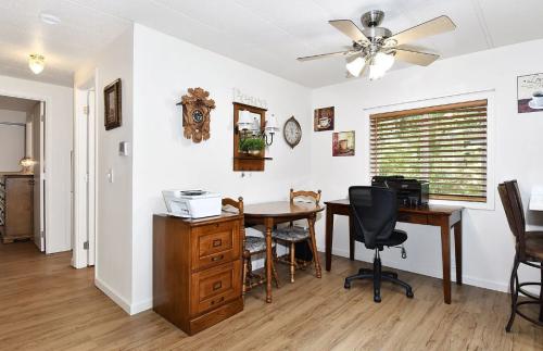 A room with a desk, chair and fan.