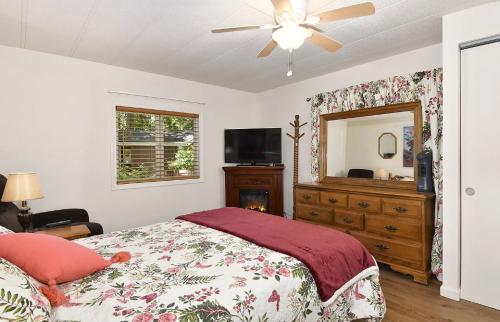 A bedroom with a bed, dresser and ceiling fan.