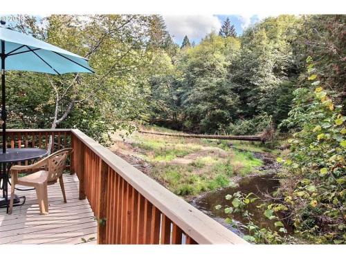 A deck with an umbrella overlooking a stream and woods.