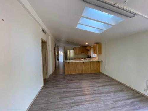 An empty kitchen with wood floors and a skylight.