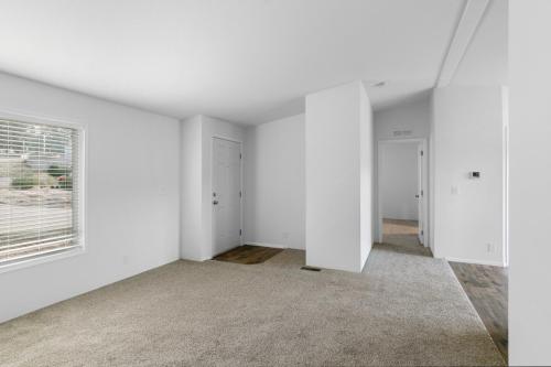 Empty living room with white walls and carpet.