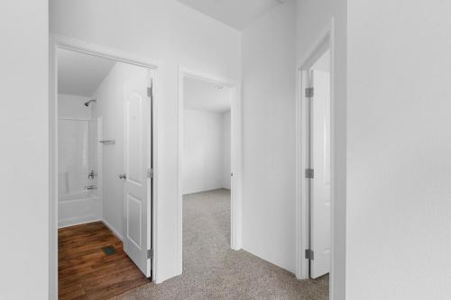 A white hallway with a wooden floor and a door.