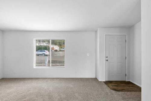 Empty living room with white walls and carpet.